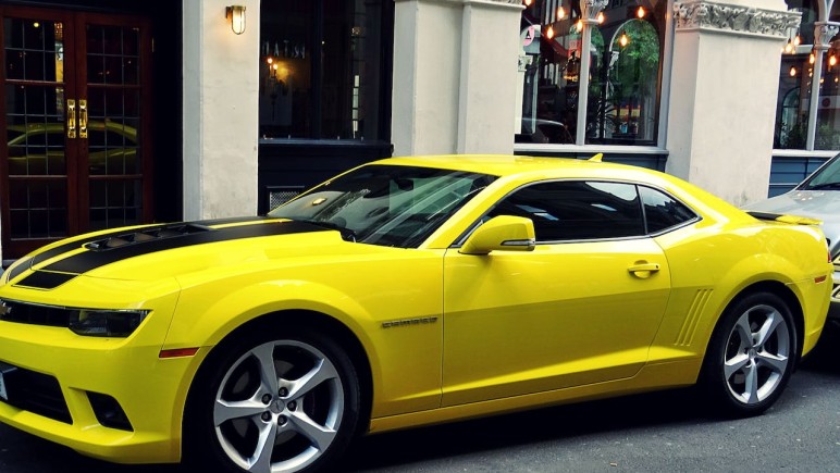YELLOW CHEVROLET CAMARO PARKED OUTSIDE BUILDING