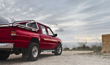 RED PICK UP TRUCK PARKED NEAR WALL