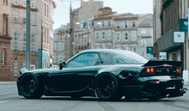 A BLACK MAZDA CAR PARKED ON STREET