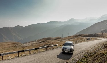 CADILLAC BLACK CAR PARKED ON ROAD NEAR MOUNTAIN