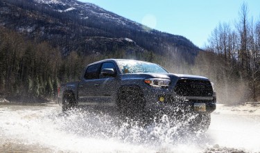 TOYOTA TACOMA DRIVING THROUGH PUDDLE ON DIRT ROAD 