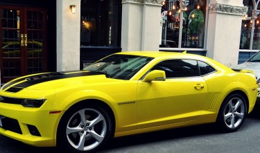 YELLOW CHEVROLET CAMARO PARKED OUTSIDE BUILDING