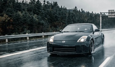 NISSAN A BLACK CAR ON WET ASPHALT ROAD 