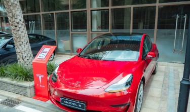 RED TESLA CAR PARKED OUTSIDE A BUILDING