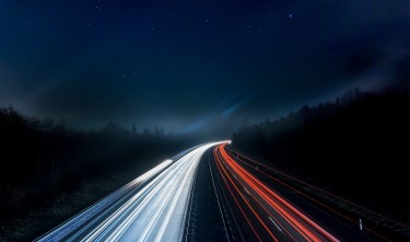 LIGHT TRAILS ON HIGHWAY AT NIGHT