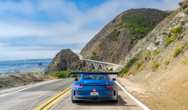 BLUE SPORTS CAR ON ROAD SEA COAST