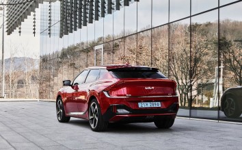 THE LEFT REAR SIDE OF THE KIA EV6 GT PARKED IN FRONT OF A BUILDING