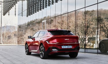 THE LEFT REAR SIDE OF THE KIA EV6 GT PARKED IN FRONT OF A BUILDING