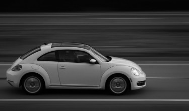 VOLKSWAGEN NEW BEETLE SPEEDING DOWN THE ROAD