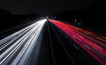 LIGHT TRAILS ON HIGHWAY AT NIGHT