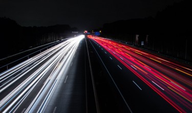 LIGHT TRAILS ON HIGHWAY AT NIGHT