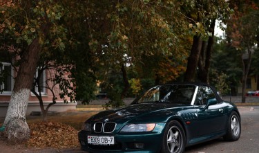 CONVERTIBLE BMW CAR PARKED ON THE STREET NEAR TREES