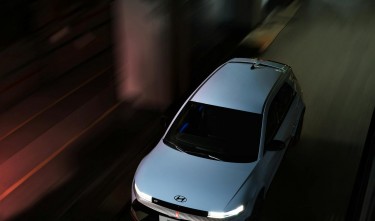 A HYUNDAI IONIQ 5 DRIVING ON A STREET AT NIGHT