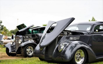 BLACK CLASSIC CARS ON SHOW ON A GRASS FIELD 