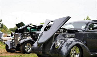 BLACK CLASSIC CARS ON SHOW ON A GRASS FIELD 