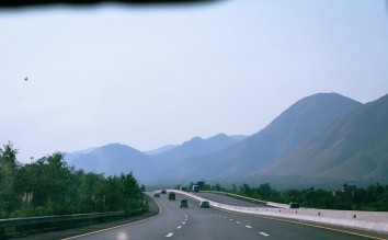 WIDE HIGHWAY NEAR MOUNTAINS ON FOGGY DAY 