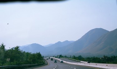 WIDE HIGHWAY NEAR MOUNTAINS ON FOGGY DAY 