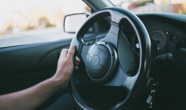 PERSON HOLDING A BLACK MITSUBISHI MOTORS STEERING WHEEL