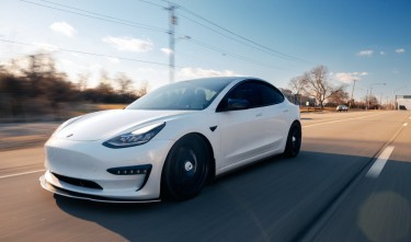 WHITE TESLA DRIVING ON THE ROAD