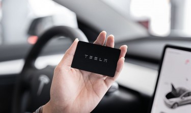 A PERSON HOLDING A TESLA BLACK CARD 