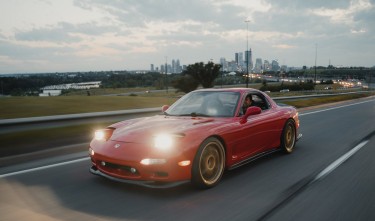 RED CAR DRIVING ON ASPHALT ROAD