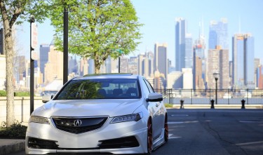 WHITE ACURA SEDAN ON GRAY ASPHALT ROAD NEAR GREEN TREE AT DAYTIME