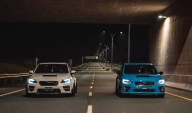 BLUE AND WHITE SPORTS CAR RIDING ON EMPTY ROAD AT NIGHT