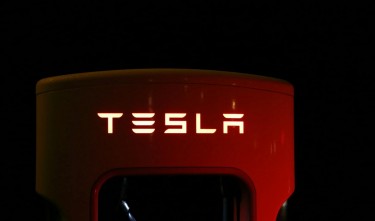 TESLA CLOSE UP OF ILLUMINATED TEXT AGAINGS BLACK BACKGROUND