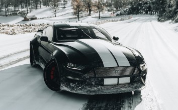 A BLACK AND WHITE FORD SHELBY MUSTANG ON SNOW COVERED ROAD 