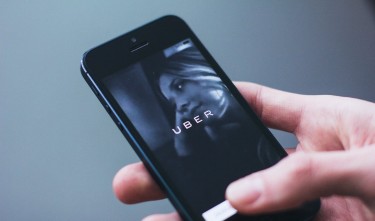 PERSON HOLDING SMARTPHONE  WITH UBER LOGO